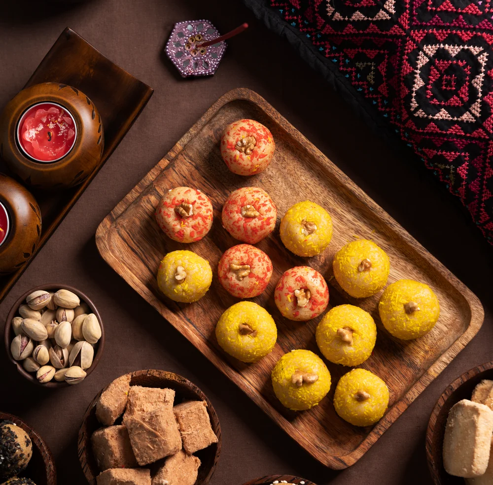 A festive spread of laddoos, barfi and dry fruits on wooden trays